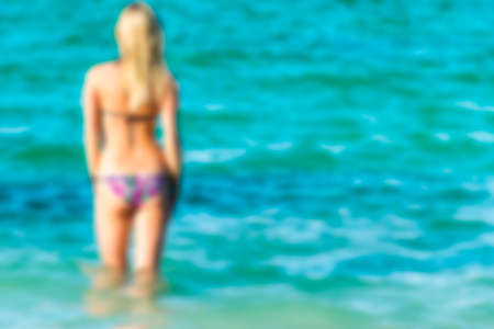 Blurred background of a Sexy back of a beautiful woman on tropical beach in small sexy bikini. Blur oceanの写真素材