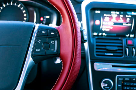 Media control buttons on the red steering wheel in black leather with computer monitor, modern car interiorの写真素材