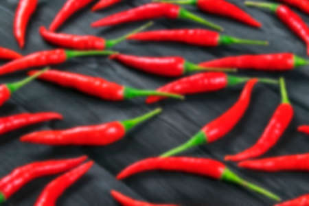 Blurred background with Red chili pepper on the blur dark wood kitchen tableの写真素材