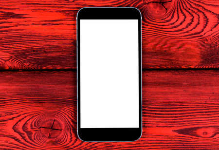 Mobile phone with blank screen mock up isolated on red wood table background. Smartphone on wood table. Smartphone white screenの写真素材