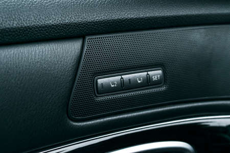 Power seat control buttons of a passenger car, modern car interior details with black perforated...