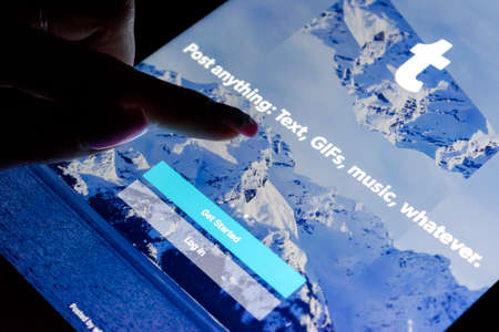 Sankt-Petersburg, Russia, December 21, 2017:  A woman's hand is touching screen on tablet iPad Pro at night with Internet service Tumblr on the screen. Tumblr is microblogging and social networking service.のeditorial素材