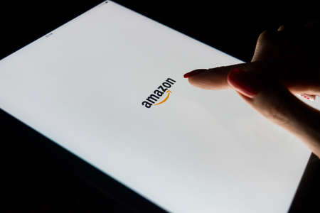 Sankt-Petersburg, Russia, January, 9 2017:  A woman's hand is touching screen on Apple iPad Pro at night with Amazon.com homepage application. Amazon is the largest online seller and trading platformのeditorial素材