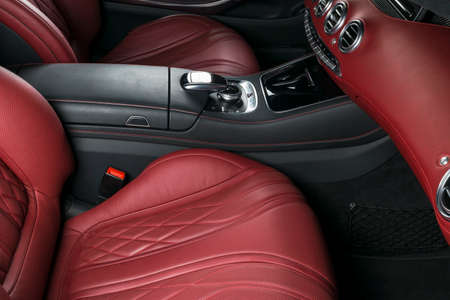 Modern Luxury car inside. Interior of prestige modern car. Comfortable leather seats. Red perforated leather cockpit. Steering wheel and dashboard. automatic gear stick shift. Car interior detailsの写真素材
