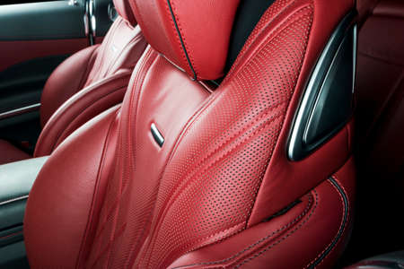 Modern Luxury car inside. Interior of prestige modern car. Comfortable leather red seats. Red perforated leather cockpit with isolated Black background. Modern car interior detailsの写真素材