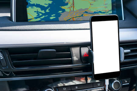 Smartphone in a car use for Navigate or GPS. Driving a car with Smartphone in holder. Mobile phone with isolatede white screen. Blank empty screen. copy space. Empty space for text. modern car interior details.の写真素材