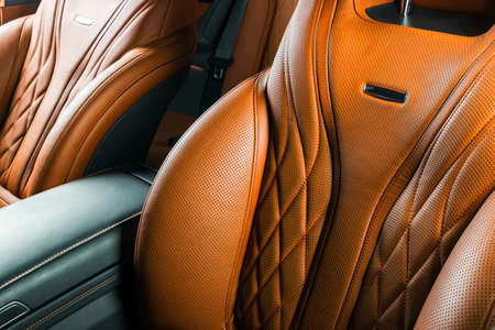 Modern Luxury car inside. Interior of prestige modern car. Comfortable leather red seats. Orange perforated leather cockpit with isolated Black background. Modern car interior detailsの写真素材