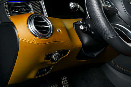 AC Ventilation Deck in Luxury modern Car Interior. Modern car interior details with orange and black leatherwith orange stitching. Carbon panel. Perforated leather steering wheelの写真素材
