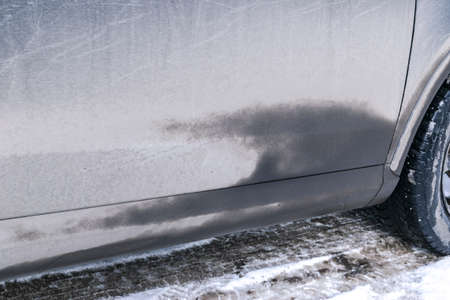Side view of a very dirty car. Fragment of a dirty SUV. Dirty doors, wheel and bumper of the off-road car with swamp splashes on a side panelの写真素材