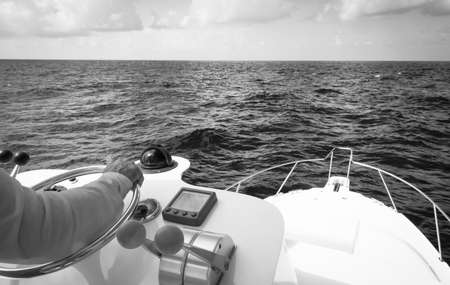 Hand of captain on steering wheel of motor boat in the blue ocean during the fishery day. Success fishing concept. Ocean yacht. Black and whiteの写真素材