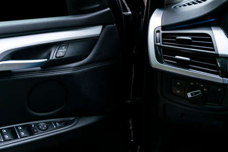 Door handle with Power windows control buttons of a luxury passenger car. Black leather interior of the luxury modern car. Modern car interior details. Car detailingの写真素材