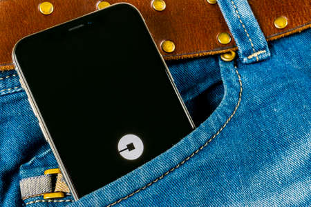 Sankt-Petersburg, Russia, April 14, 2018: Uber application icon on Apple iPhone X screen close-up in jeans pocket. Uber app icon. Uber is taxi car transportationのeditorial素材