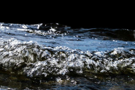 Big windy waves splashing over rocks. Wave splash in the lake on black background. Waves breaking on...