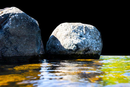 Big windy waves splashing over rocks. Wave splash in the lake isolated on black background. Waves breaking on a stony beach, forming a spray. Water splashes. Water surface textureの写真素材