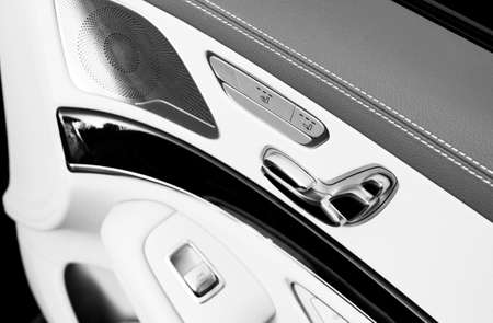 Door handle with Power seat contol buttons of a luxury passenger car. White leather interior of the luxury modern car. Modern car interior details. Car detailing. Black and whiteの写真素材
