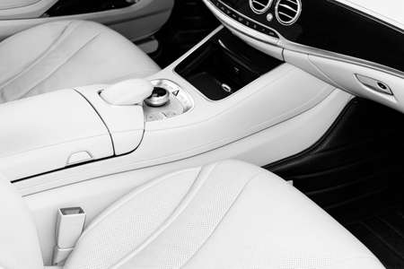 White leather interior of the luxury modern car. Leather comfortable white seats and multimedia. Steering wheel and dashboard. Automatic gear shift. Car interior details. Car detailing. Black and whiteの写真素材