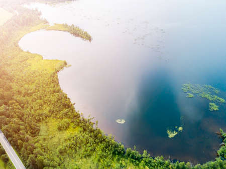 Aerial view of highway. Aerial view of a country road near the lake. Car passing by. Aerial road. Aerial view flying. Captured from above with a drone. Soft lightingの写真素材