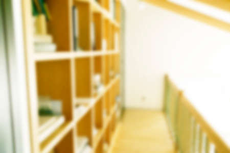 Abstract blurred modern white bookshelves with books. Blur manuals and textbooks on bookshelves in library or in book store. Concept for education. Home interior blur bokeh background.の写真素材
