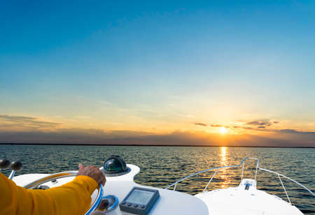 Hand of captain on steering wheel of motor boat in the blue ocean during the fishery day. Success fishing concept. Ocean yachtの写真素材