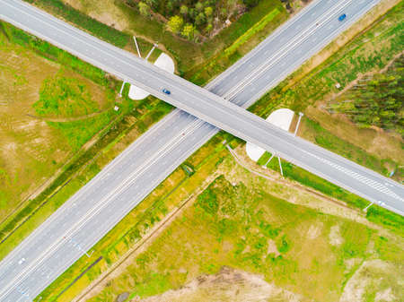 Aerial view of highway in city. Cars crossing interchange overpass. Highway interchange with traffic. Aerial bird's eye photo of highway. Expressway. Road junctions. Car passing. Top view from above.の写真素材