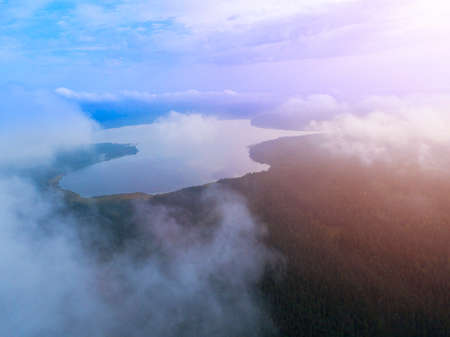 Aerial Drone view clouds over the green forest and lake. Low lying cloud. Aerial view of over...