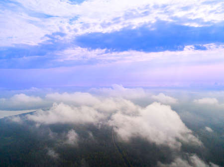 Aerial Drone view clouds over the green forest and lake. Low lying cloud. Aerial view of over...