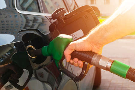 Refueling the car at a gas station fuel pump. Man driver hand refilling and pumping gasoline oil the car with fuel at he refuel station. Car refueling on petrol station. Fuel pump at stationのeditorial素材