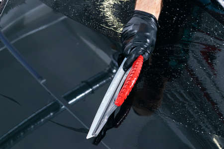 A man cleaning car with microfiber cloth, car detailing (or valeting) concept. Selective focus. Car...