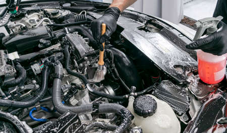 Cars in a carwash. Car wash with foam at station. Carwash. Washing at the station. Car washing concept. Car detailing. A man cleaning car. Worker cleaning. Cleaning engine with the foam and a brushの写真素材