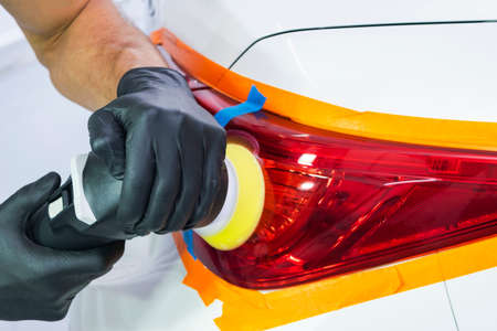 Car polish wax worker hands holding polisher and polish. Close up at hand holding car polisher. Man holds a polisher in the hand and polishes the car. Car detailingの写真素材