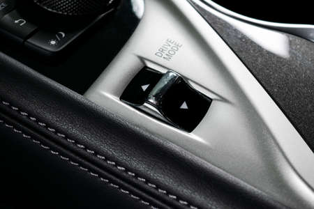 Track control buttons near automatic gear stick of a modern car in black leather interior with...