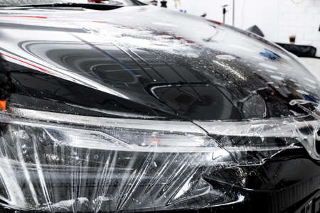 Car wrapping specialist putting vinyl foil or film on car. Protective film on the car. Applying a...