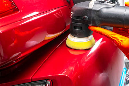 Car polish wax worker hands applying protective tape before polishing. Buffing and polishing car....