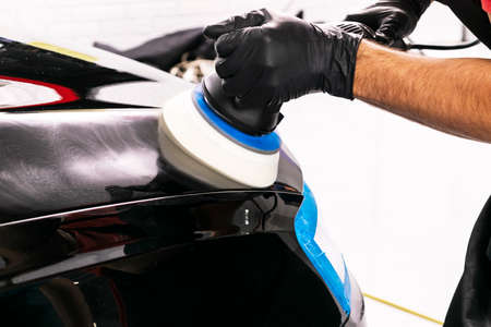 Car polish wax worker hands applying protective tape before polishing. Buffing and polishing car....