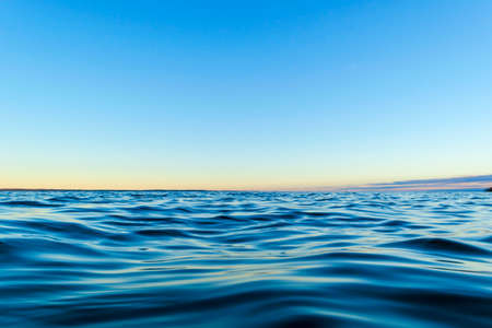 Water surface. View of a Sunset sky background. Dramatic gold sunset sky with evening sky clouds over the sea. View of a Crystal clear sea water texture. Landscape. Small waves. Water reflectionの写真素材