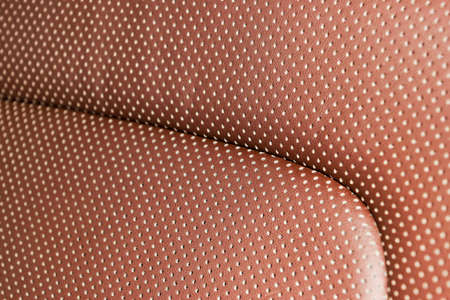 Modern luxury Car brown leather interior. Part of leather car seat details with white stitching....