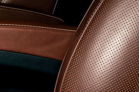 Modern luxury Car brown leather interior. Part of leather car seat details with white stitching. Interior of prestige car. Comfortable perforated leather seats. Brown perforated leather.の写真素材