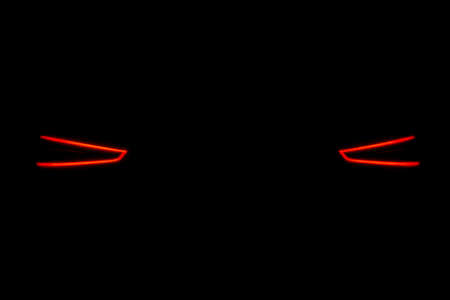 Rear car lights on a black background. Cars light trails. Night city road with traffic headlight. Light up road by vehicle. Car lights at nightの写真素材