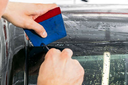 Car wrapping specialist putting vinyl foil or film on car. Protective film on the car. Applying a...