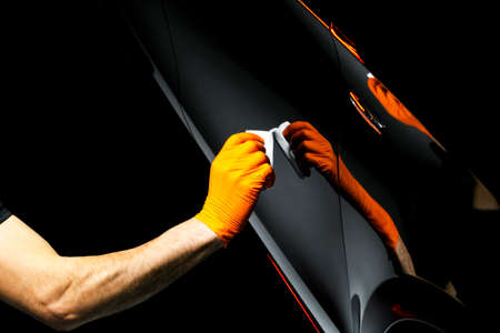 Car polish wax worker hands polishing car. Buffing and polishing vehicle with ceramic. Car...