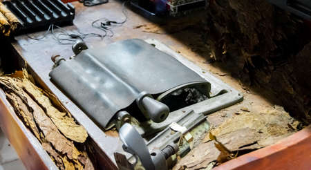A cigar rolling machine Inside a cigar factory. Traditional manufacture of cigars at the tobacco...