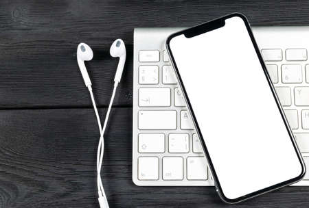 Smartphone with blank screen mock up. Smartphone isolated screen. Mobile phone white screen with copy space on computer keyboard. Empty space for text. Isolated white screenの写真素材