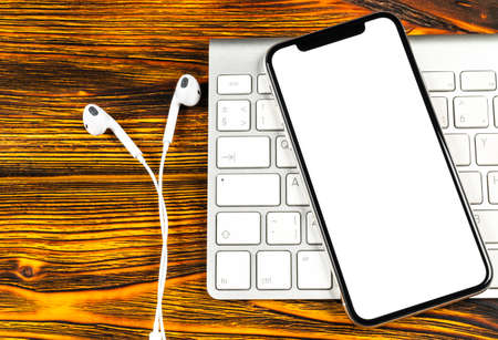 Smartphone with blank screen mock up. Smartphone isolated screen. Mobile phone white screen with copy space on computer keyboard. Empty space for text. Isolated white screenの写真素材