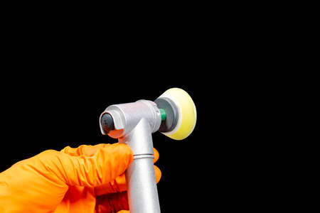 Car polish wax worker hands holing polishing tools in protective gloves isolated on black background. Buffing and polishing car concept. Man holds a polisher in the hand and polishes.の写真素材