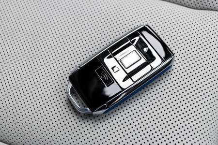 Closeup inside vehicle of wireless blue leather key ignition on white leather seat. Wireless start...