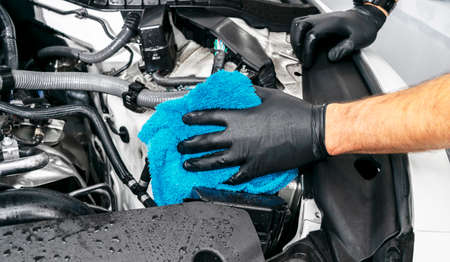 A man cleaning car engine with microfiber cloth. Car detailing or valeting concept. Selective focus. Car detailing. Cleaning with sponge. Worker cleaning. Car wash concept solution to cleanの写真素材