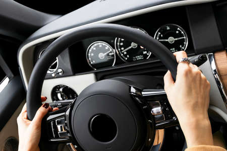 Woman's hands on the steering wheel driving modern luxury car. Concept woman driving. Hands holding...