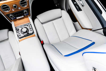 Modern luxury car white leather interior with natural wood panel. Part of leather car seat details...