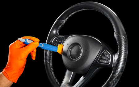 A man cleaning car steering wheel with brush. Car detailing or valeting concept. Selective focus....