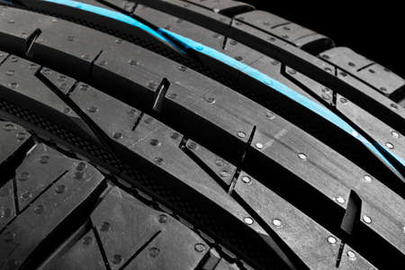 Studio shot of a set of summer car tires on black background. Tire stack background. Car tyre...